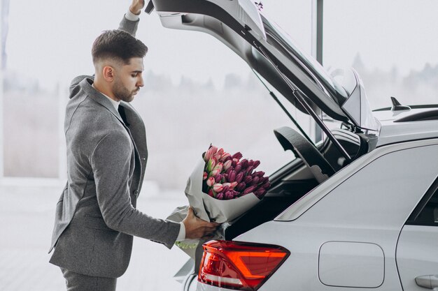 Hombre de negocios guapo joven que entrega ramo de flores hermosas