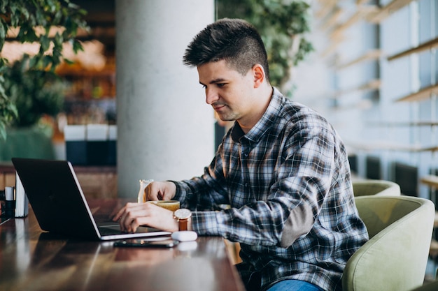 Hombre de negocios guapo joven usando laptop en un café