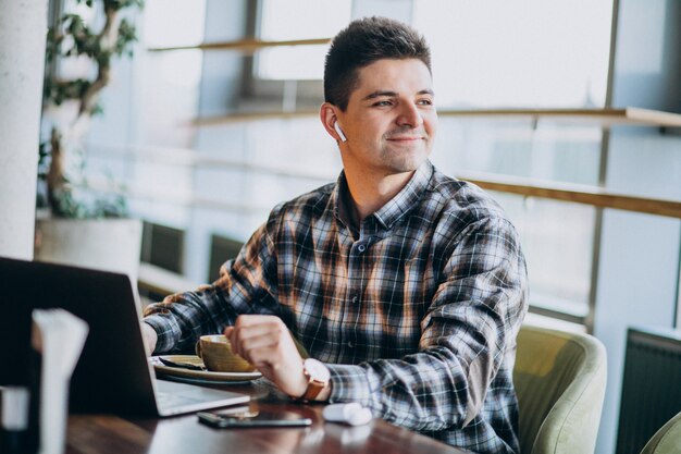 Hombre de negocios guapo joven usando laptop en un café