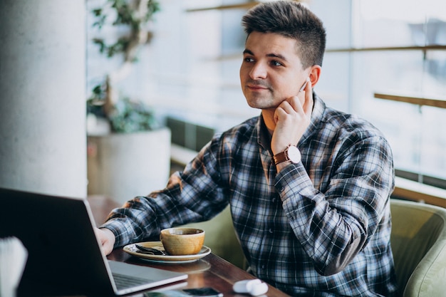 Hombre de negocios guapo joven usando laptop en un café