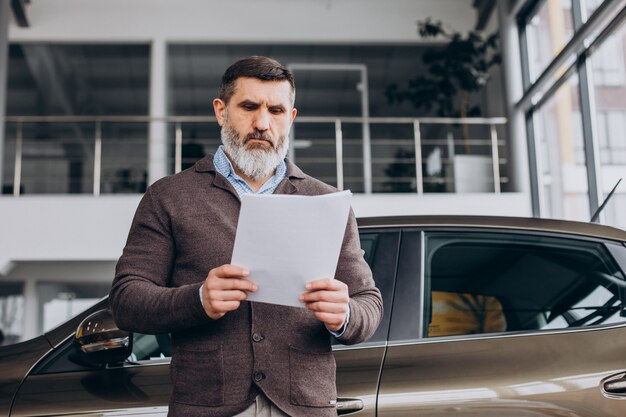 Hombre de negocios guapo leyendo documentos sobre alquiler de coches