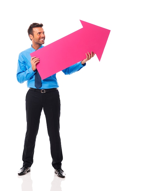 Hombre de negocios guapo sosteniendo una flecha rosa y apuntando al espacio de la copia