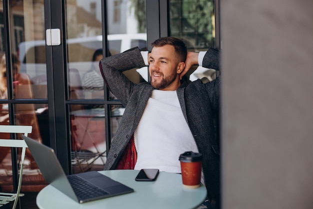 Hombre de negocios guapo trabajando en la computadora portátil en la cafetería