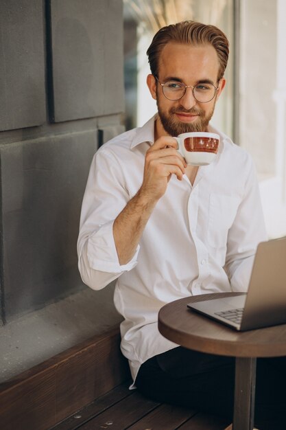 Hombre de negocios guapo trabajando en línea en la computadora de la cafetería