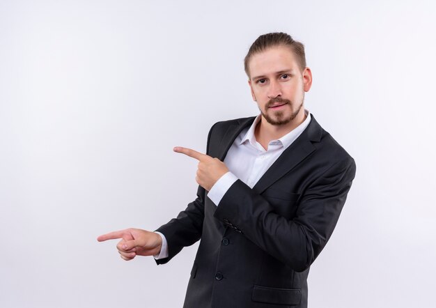 Hombre de negocios guapo vestido con traje de pie sobre fondo blanco.