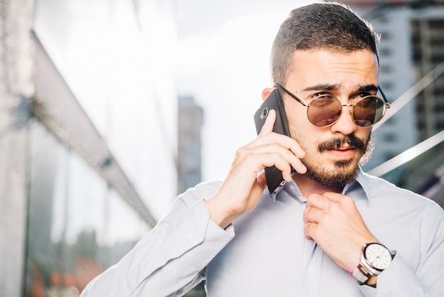 Hombre de negocios hablando por teléfono y ajustar el cuello