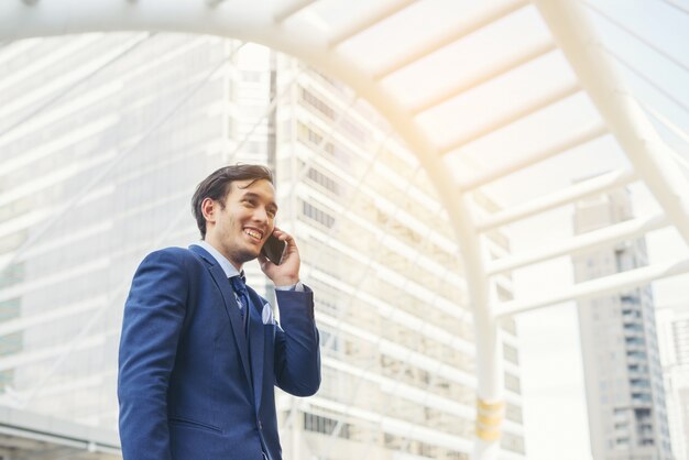 Hombre de negocios hablando por teléfono celular contra el edificio al aire libre.