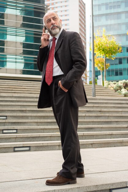 Hombre de negocios hablando por teléfono celular y mirando a otro lado