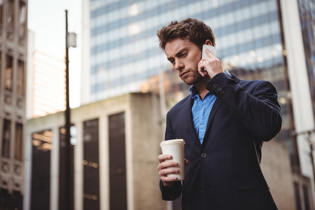 Hombre de negocios hablando por teléfono móvil y sosteniendo café