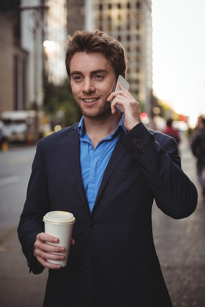 Hombre de negocios hablando por teléfono móvil y sosteniendo café