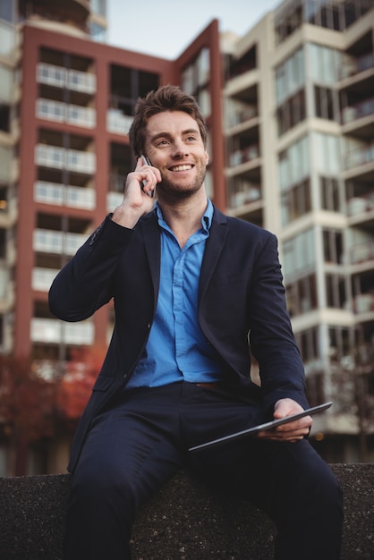 Hombre de negocios hablando por teléfono móvil y sosteniendo tableta digital