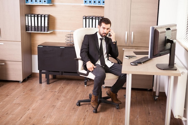 Hombre de negocios hablando por teléfono y trabajando en la oficina. Empresario en entorno profesional