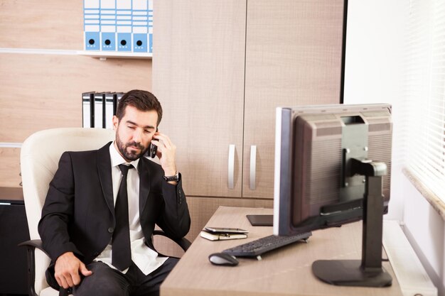 Hombre de negocios hablando por teléfono y trabajando en la oficina. Empresario en entorno profesional