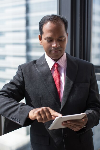 Hombre de negocios indio serio que usa la tableta digital