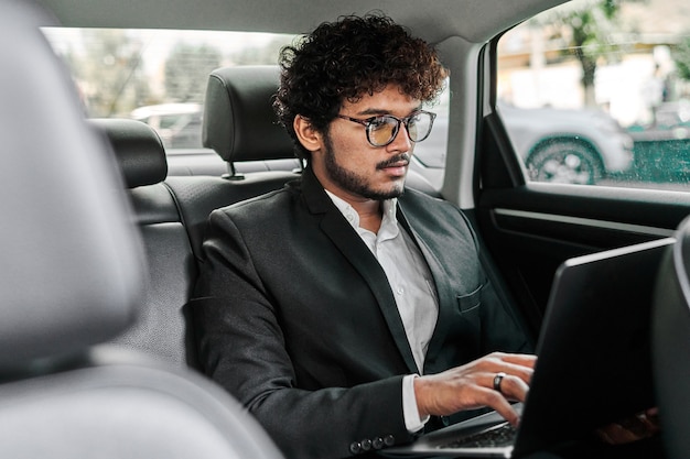 Hombre de negocios indio trabajando en el asiento trasero.