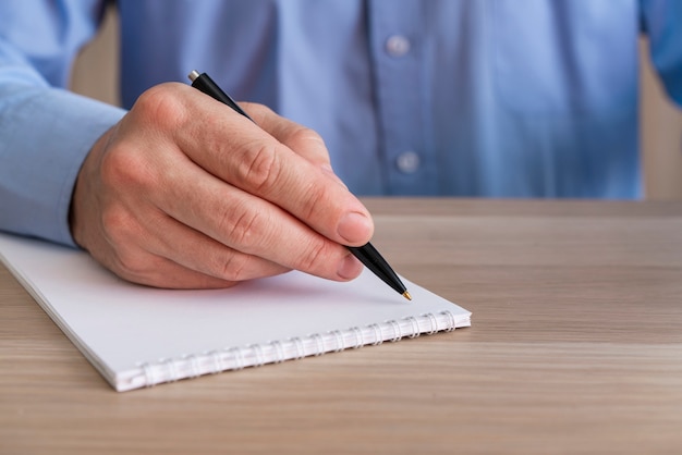 Hombre de negocios irreconocible escribiendo en el bloc de notas