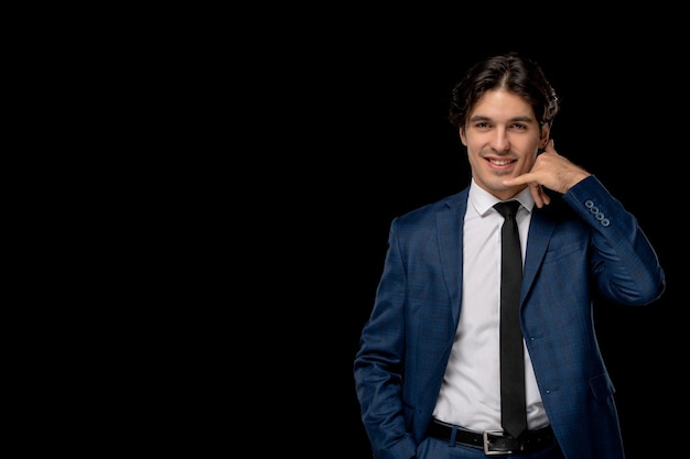 Hombre de negocios joven apuesto en traje azul oscuro con la corbata mostrando gesto de llamada