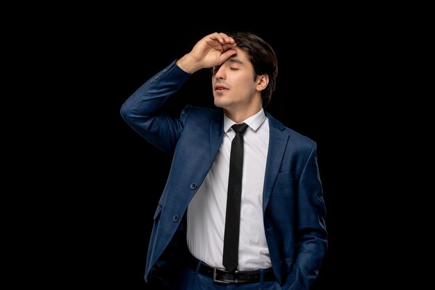 Hombre de negocios joven apuesto en traje azul oscuro con la corbata tocando la frente