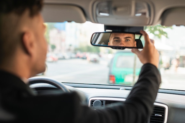 Hombre de negocios joven arreglando su espejo retrovisor