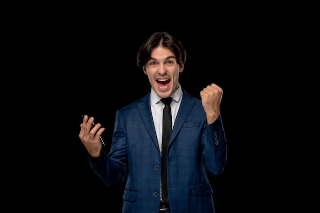 Hombre de negocios joven emocionado hombre guapo en traje azul oscuro con la corbata sosteniendo el teléfono