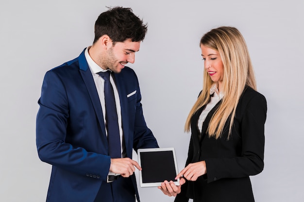 Hombre de negocios joven y empresaria que señalan su finger en la tableta digital contra el contexto gris