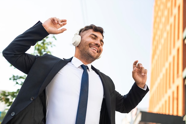 Hombre de negocios joven escuchando música y bailando