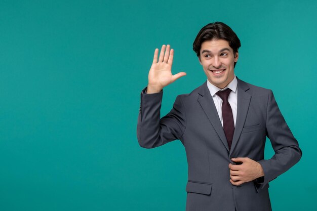 Hombre de negocios joven guapo lindo en traje de oficina gris y corbata saludando