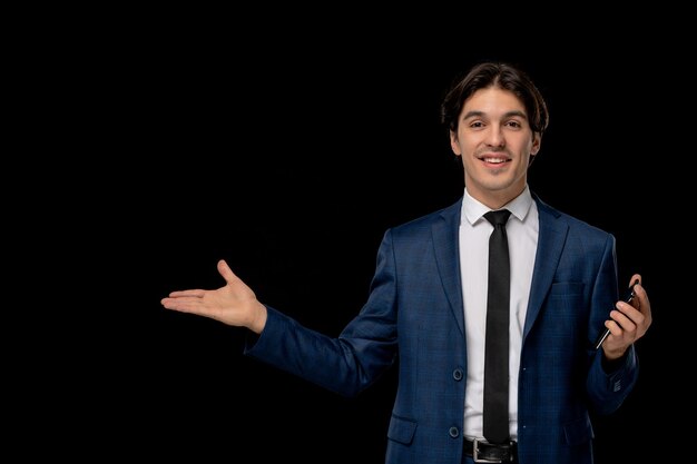 Hombre de negocios joven guapo sonriente en traje azul oscuro con la corbata sosteniendo el teléfono