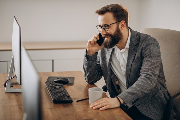 Hombre de negocios joven hablando por teléfono y trabajando en equipo