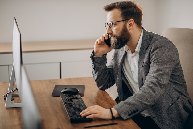 Hombre de negocios joven hablando por teléfono y trabajando en equipo