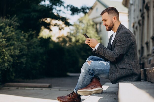 Hombre de negocios joven hermoso que usa el teléfono fuera de la calle