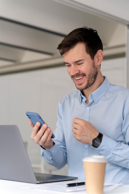 Hombre de negocios joven que trabaja en su escritorio con ordenador portátil y smartphone