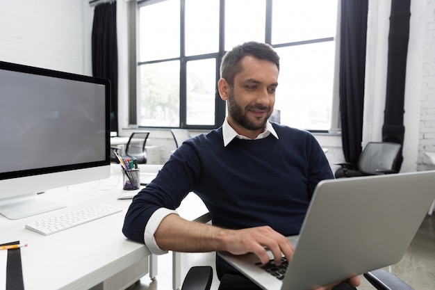 Hombre de negocios joven sonriente que usa la computadora portátil