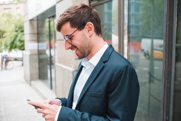 Hombre de negocios joven sonriente que usa smartphone