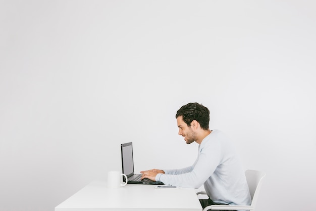 Foto gratuita hombre de negocios joven y sonriente trabajando con el portátil