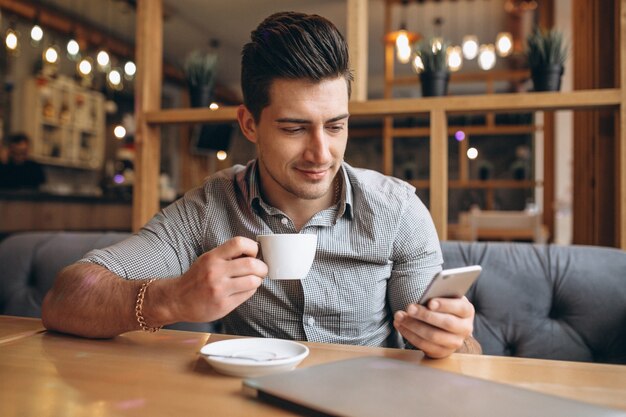 Hombre de negocios joven con teléfono en un café