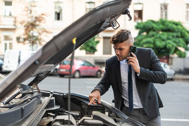 Hombre de negocios joven tratando de arreglar su coche