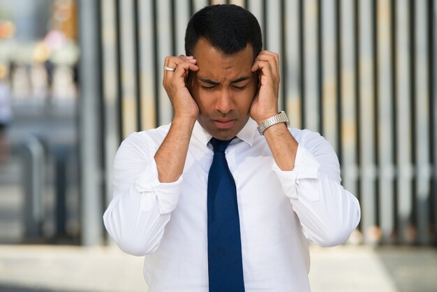 Hombre de negocios latino tensionado que lleva a cabo la pista con las manos