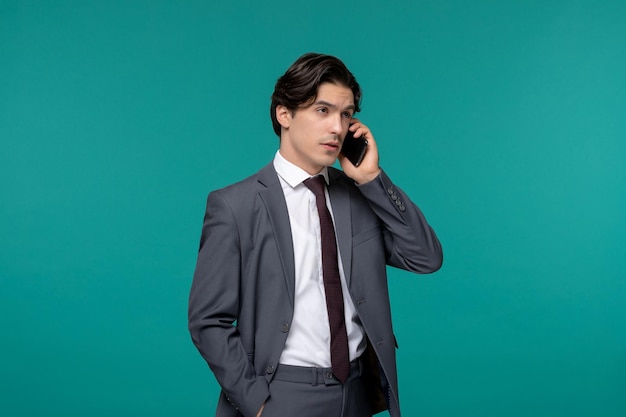 Hombre de negocios lindo joven guapo en traje de oficina gris y corbata haciendo llamadas telefónicas