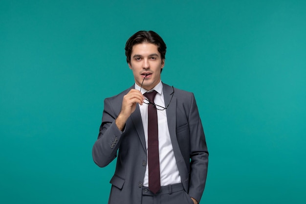 Hombre de negocios lindo joven guapo en traje de oficina gris y corbata mordiendo la esquina de las gafas