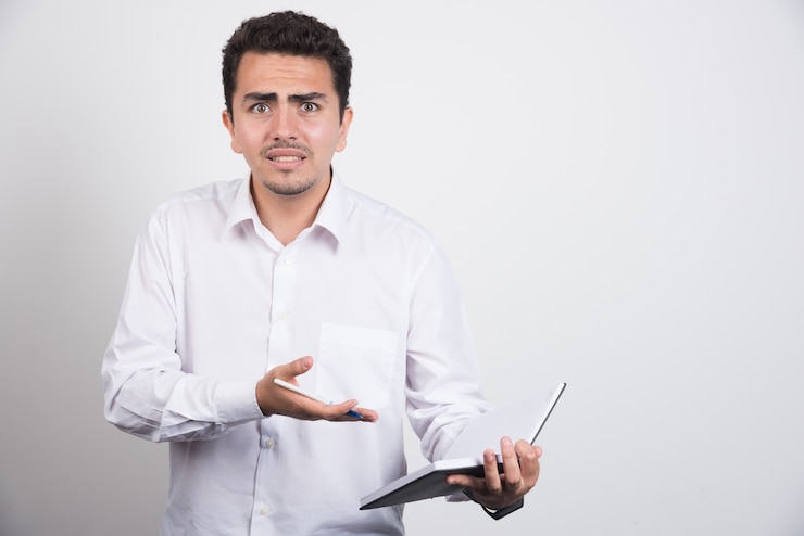 Foto gratuito hombre de negocios loco apuntando al cuaderno sobre fondo blanco.