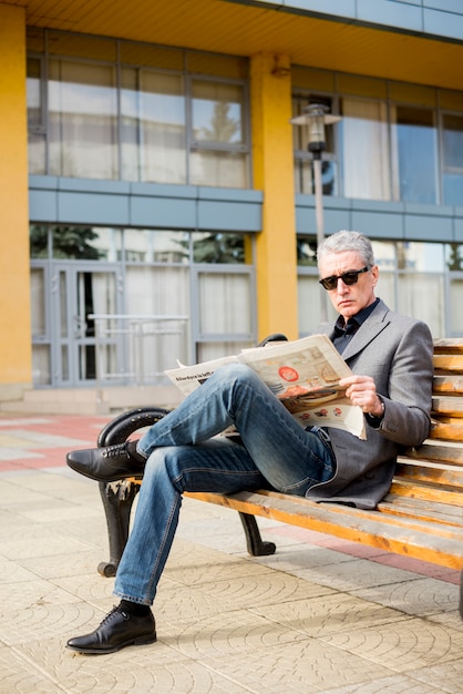 Foto gratuita hombre de negocios maduro leyendo periódico