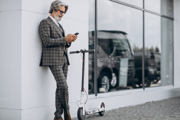 Hombre de negocios de mediana edad montando scooter en un elegante traje