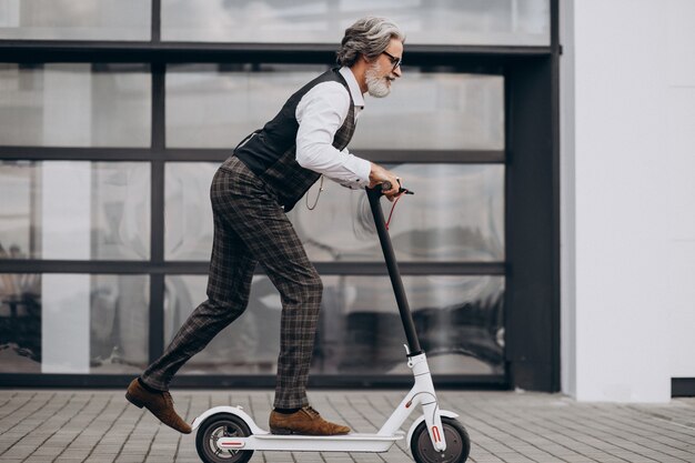 Hombre de negocios de mediana edad montando scooter en un elegante traje