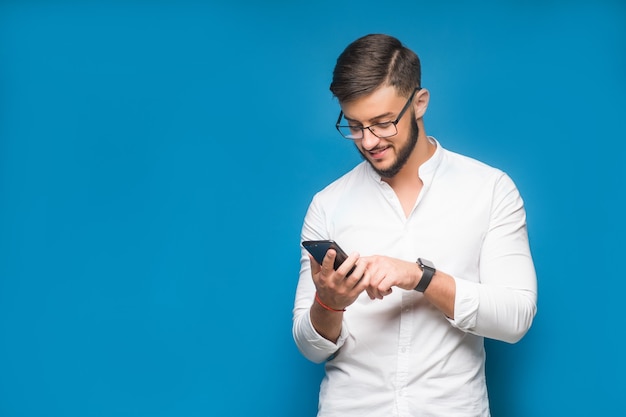 Hombre de negocios mediante mensajes de texto de aplicación de teléfono móvil en el azul