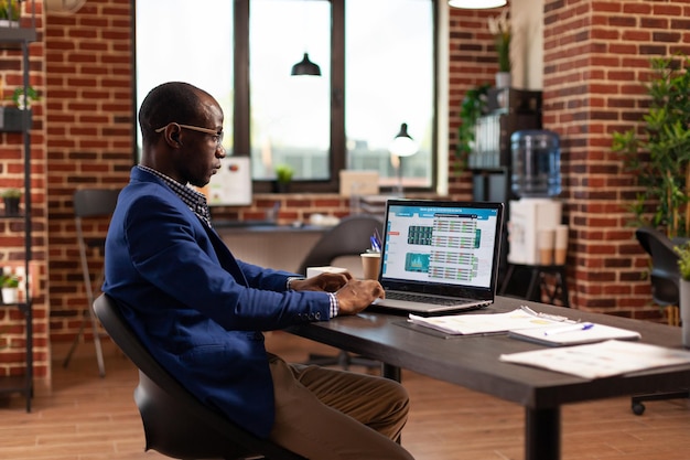 Hombre de negocios mirando la tabla de datos para hacer un análisis bursátil para el crecimiento de la empresa en la computadora portátil. Emprendedor que busca en el comercio mundial de dinero para invertir en criptomonedas y trabajar en un proyecto.