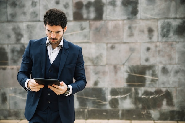 Hombre de negocios moderno usando tableta enfrente de muro