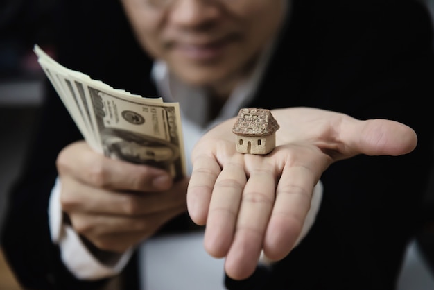 El hombre de negocios muestra dinero El billete de banco hace que el plan financiero invite a la gente a vender o comprar una casa y un automóvil - concepto de seguro de crédito de préstamo de propiedades monetarias