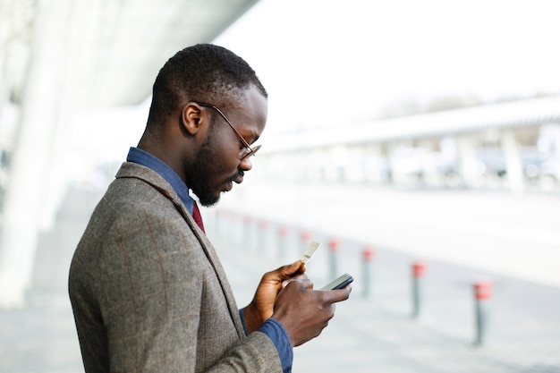 El hombre de negocios negro afroamericano elegante mecanografía la información de su tarjeta de crédito