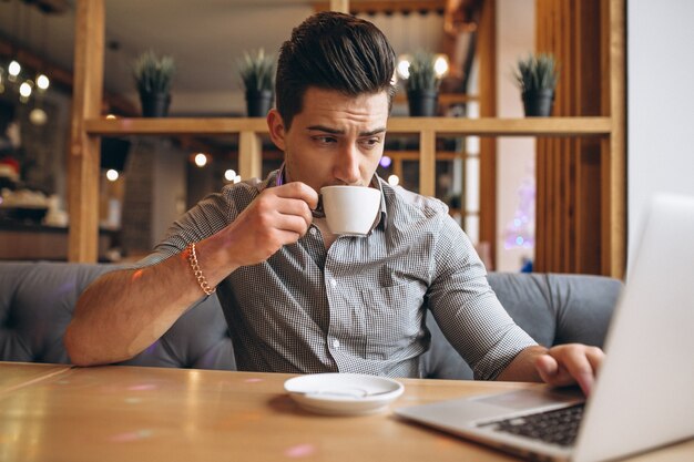 Hombre de negocios con ordenador portátil tomando café en una cafetería